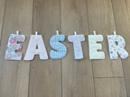Easter letter banner spelling 'EASTER' in pastel patterned fabric, laid out on a light wood floor.